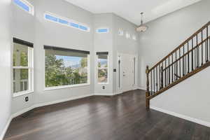 Foyer with stairway, a high ceiling, dark wood-type flooring, and a skylight