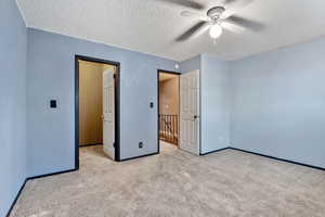 Unfurnished bedroom featuring carpet floors, ceiling fan, and a textured ceiling