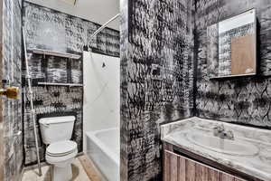 Full bathroom featuring wallpapered walls,  shower combination, vanity, and tile patterned floors