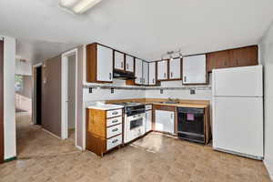 Kitchen with white appliances, light countertops, and white cabinetry