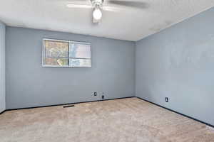 Spare room with carpet, a textured ceiling, and a ceiling fan