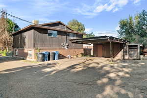 Back of property with brick siding, a detached carport, and driveway