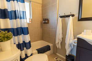 Bathroom with shower / bath combo, vanity, and light tile patterned flooring