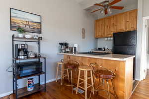 Kitchen with a peninsula, a kitchen breakfast bar, light wood-type flooring, light countertops, and beam ceiling