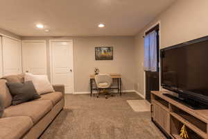 Living area with light colored carpet, an office area, and recessed lighting