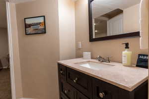 Bathroom with a textured wall, vanity, and light carpet