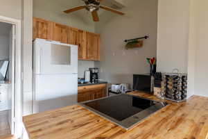 Kitchen featuring freestanding refrigerator, black electric cooktop, wood finished floors, and wooden counters