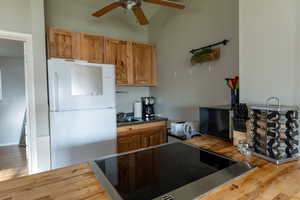 Kitchen with freestanding refrigerator, butcher block countertops, wood finished floors, and brown cabinets