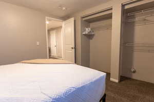 Bedroom featuring dark colored carpet and two closets