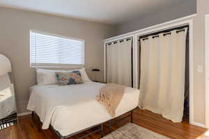 Bedroom featuring dark wood-type flooring and multiple closets