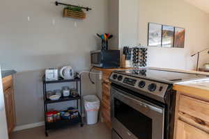 Kitchen with appliances with stainless steel finishes, light tile patterned flooring, brown cabinets, and light countertops