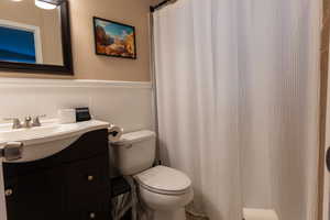 Full bathroom with vanity, wainscoting, and a shower with curtain