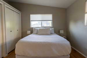 Bedroom with wood finished floors, a closet, and vaulted ceiling