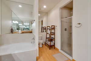 Bathroom featuring a shower stall, a garden tub, light wood-style floors, and recessed lighting