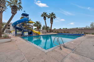 Community pool featuring a water slide and a patio area