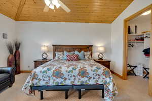 Bedroom featuring wooden ceiling, light colored carpet, vaulted ceiling, ceiling fan, and a closet