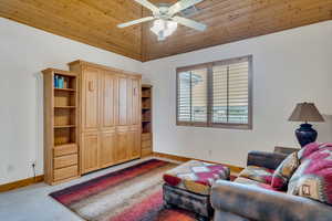 Living area with wooden ceiling, light colored carpet, high vaulted ceiling, and ceiling fan