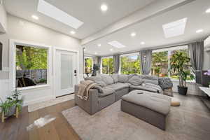 Living area with plenty of natural light, dark wood-style floors, a skylight, and recessed lighting