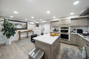 Kitchen with gray cabinets, backsplash, a center island, light wood-style flooring, and recessed lighting