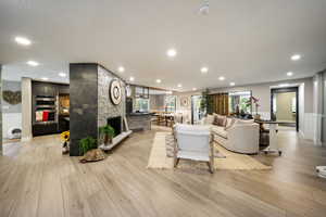 Living room with light wood finished floors, recessed lighting, and a fireplace