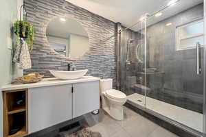 Bathroom featuring vanity, a shower stall, tile patterned flooring, and tile walls