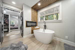 Bathroom with wood finished floors, a freestanding tub, stacked washer / dryer, recessed lighting, and ensuite bath