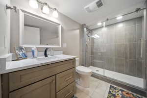 Full bath featuring vanity, light tile patterned flooring, and a stall shower