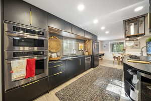 Kitchen with dark cabinetry, appliances with stainless steel finishes, recessed lighting, modern cabinets, and beverage cooler