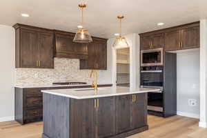 Kitchen featuring dark brown cabinets, light wood-style floors, light stone counters, and recessed lighting