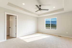 Unfurnished bedroom with a raised ceiling, carpet, ceiling fan, and recessed lighting