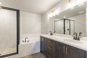 Full bath featuring a shower stall, a bath, dark tile patterned flooring, and double vanity