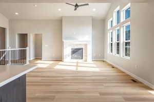 Unfurnished living room featuring recessed lighting, a ceiling fan, light wood-style flooring, and a fireplace