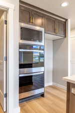 Kitchen featuring stainless steel appliances, dark brown cabinets, light wood-style flooring, recessed lighting, and a textured ceiling