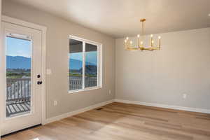 Unfurnished dining area with a mountain view, plenty of natural light, light wood-style floors, and a chandelier