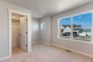Unfurnished bedroom featuring light carpet and a spacious closet