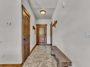 Doorway featuring stone finish flooring and baseboards