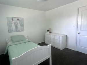 Bedroom with dark carpet and baseboards