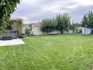 Fenced backyard featuring a hot tub, a patio area, and a storage unit