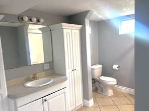 Bathroom with light tile patterned floors, vanity, a textured ceiling, and a closet