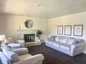 Carpeted living area with a fireplace and a textured ceiling