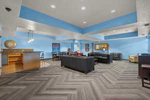 Living room featuring a raised ceiling, light colored carpet, and recessed lighting