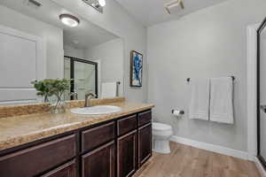 Bathroom with light wood-type flooring, vanity, a stall shower, and a textured ceiling