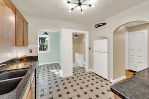 Kitchen with arched walkways, freestanding refrigerator, light floors, and black range with electric cooktop