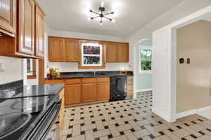 Kitchen with black appliances, arched walkways, tile flooring,  and black granite counters