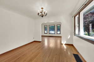 Formal dining area featuring arched walkways, hardwood floors, and a chandelier