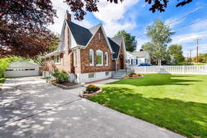 View of front of home featuring brick siding, an outbuilding, a detached garage,