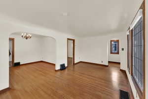 View of formal dining room with arched walkways, hard wood floors, and a chandelier