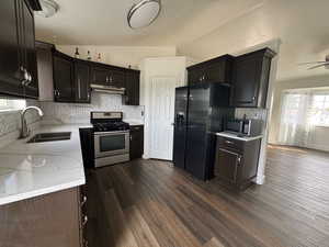 Kitchen featuring plenty of natural light, backsplash, appliances with stainless steel finishes, dark wood-type flooring, and lofted ceiling