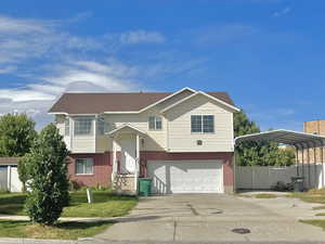 Split foyer home featuring brick siding, a carport, driveway, and an attached garage