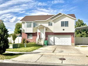 Bi-level home featuring brick siding, driveway, a gate, and a garage